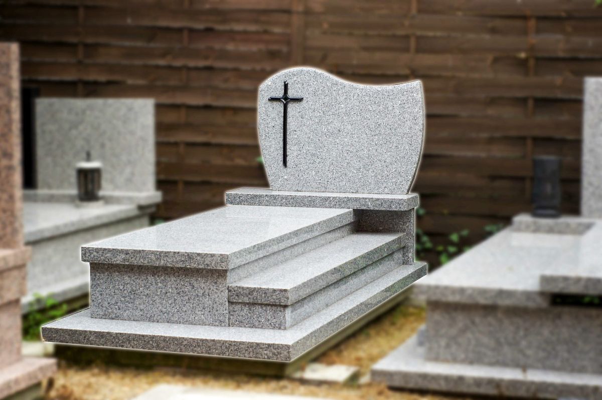 Nagrobek pojedynczy z jasnego granitu z grawerowanym krzyżem i stopniowaną podstawą